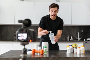 Recreatieve sporter maakt pre workout shake klaar in moderne keuken met supplementenpot en shaker