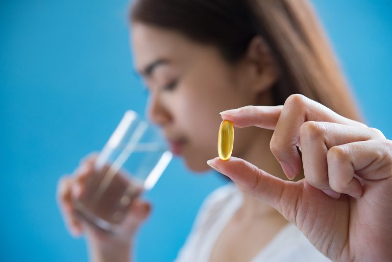Vrouw neemt omega-3 visolie capsule in met glas water