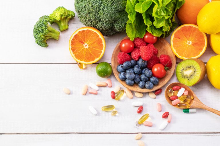 Een verzameling kleurrijke groenten, fruit, noten, zaden en supplementen op een houten ondergrond