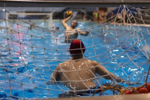 Waterpoloër schiet op doel tijdens wedstrijd met explosieve beweging boven water