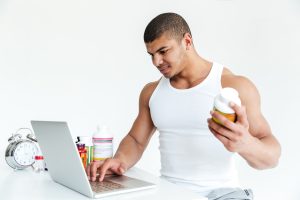 Sporter leest het ingrediëntenetiket van een supplementenpot om de werkzame stoffen te controleren