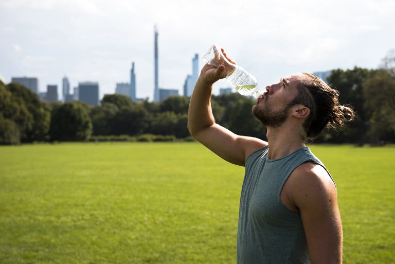 Atleet drinkt water uit een bidon tijdens een training in warm, zonnig weer