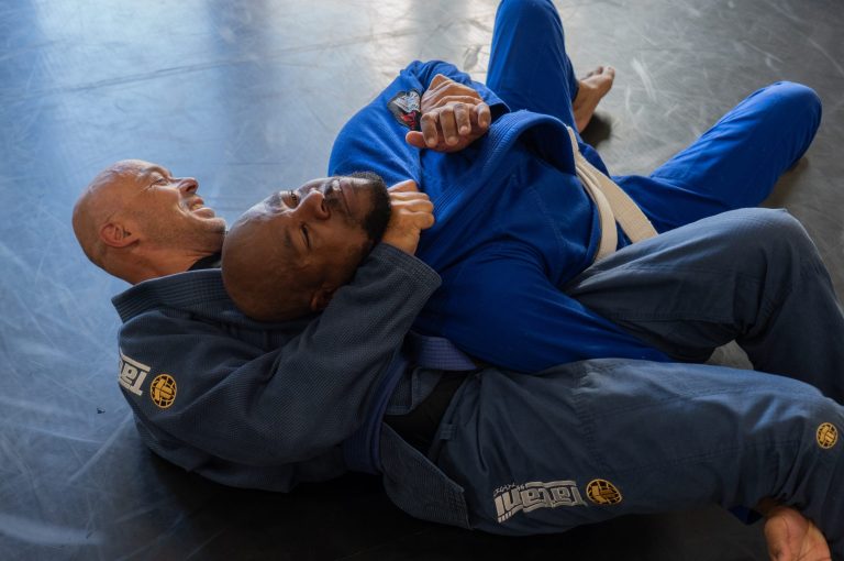 BJJ-sporter voert een gi guillotine choke uit terwijl hij tegelijkertijd een armbar aanzet tijdens sparring