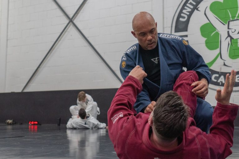 Twee BJJ-sporters sparren tijdens een les bij Unity 99 Rotterdam Academy, guard-positie met grip work