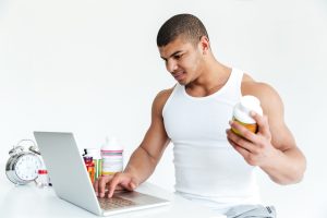 Sporter leest het ingrediëntenetiket van een supplementenpot om de werkzame stoffen te controleren